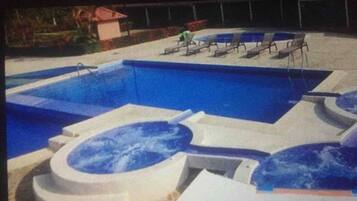 Piscina com hidromassagem e espreguiçadeiras.