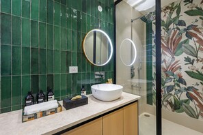 A bathroom with a round mirror, a white sink, and a floral wall design. - ELIVAAS Prassanam Vatika 2 BHK Hillside Villa with Private Pool (Faridabad)