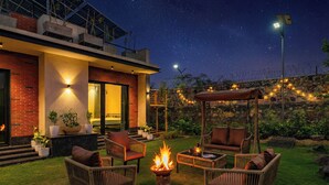 Eine Terrasse mit Korbmöbeln, einer Feuerstelle und einem Gebäude mit Backsteinfassade.