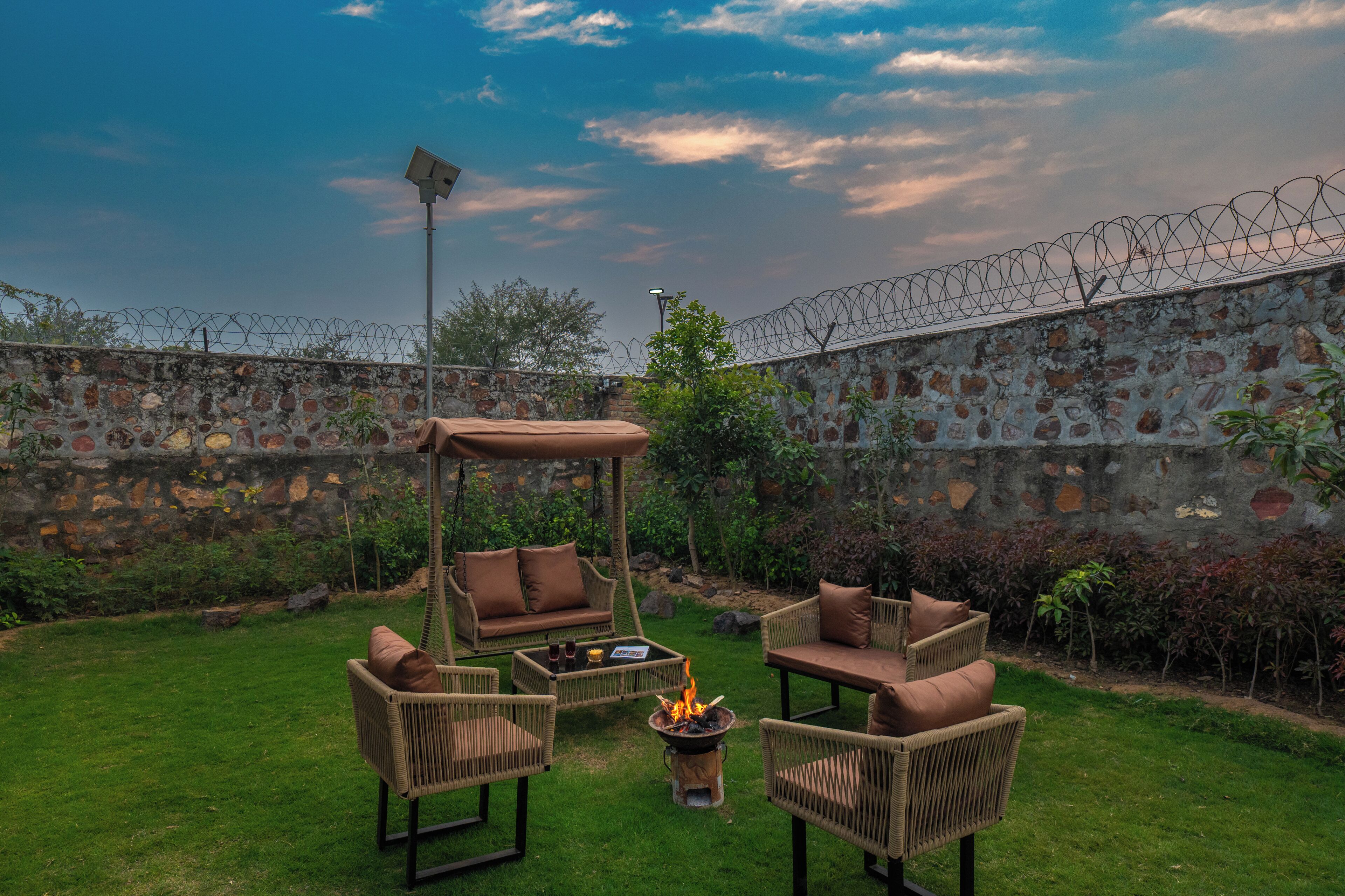 A patio with wicker furniture, a fire pit, and a stone wall with barbed wire.