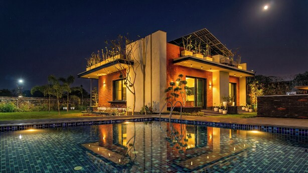 Ein modernes Haus mit Swimmingpool, umgeben von viel Grün und einem klaren Nachthimmel.