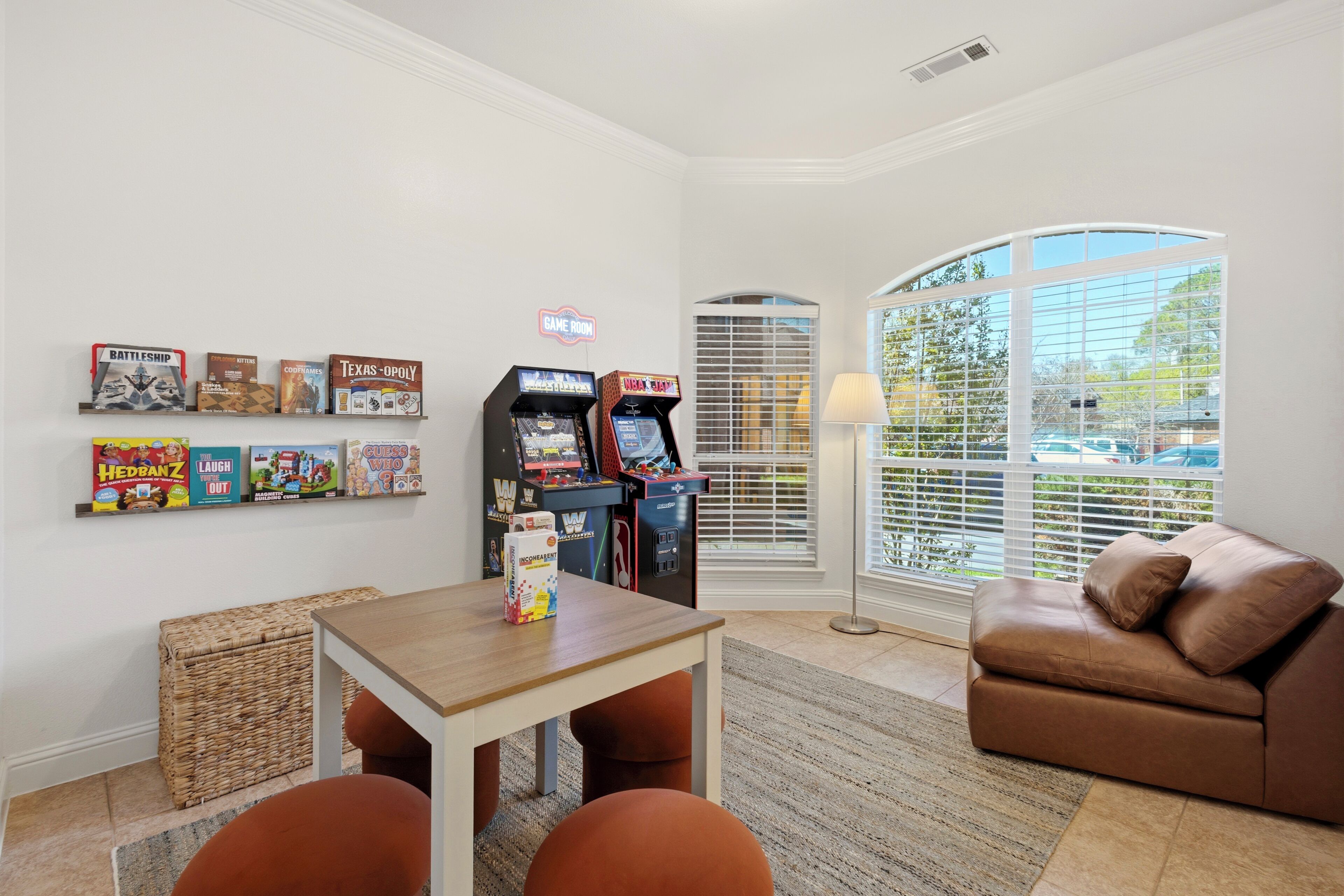 A room with a sofa, a table, and arcade games.