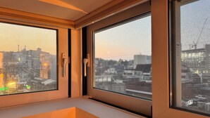 Una habitación con un ventanal grande, una puerta y vistas a un paisaje urbano.