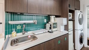 Una cocina con lavamanos, cafetera, microondas y lavadora y secadora apiladas.