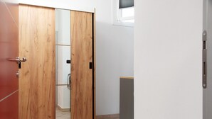 Une pièce avec une armoire en bois, une porte coulissante et une fenêtre avec des stores.