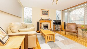 A living room with a sofa, a wooden coffee table, a fireplace, a television, and a window with blinds. - Lovely 2BR flat w balcony, Golders Green tube 5min (London)