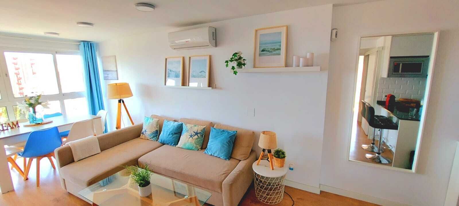 A living room with a sofa, a coffee table, a lamp, a side table, and a mirror.