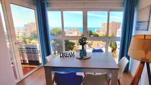 Un comedor con una mesa, sillas, una lámpara y vistas a edificios y vegetación.