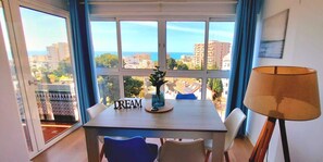 Ein Essbereich mit Tisch, Stühlen, einer Lampe und Blick auf Gebäude und Grünflächen.