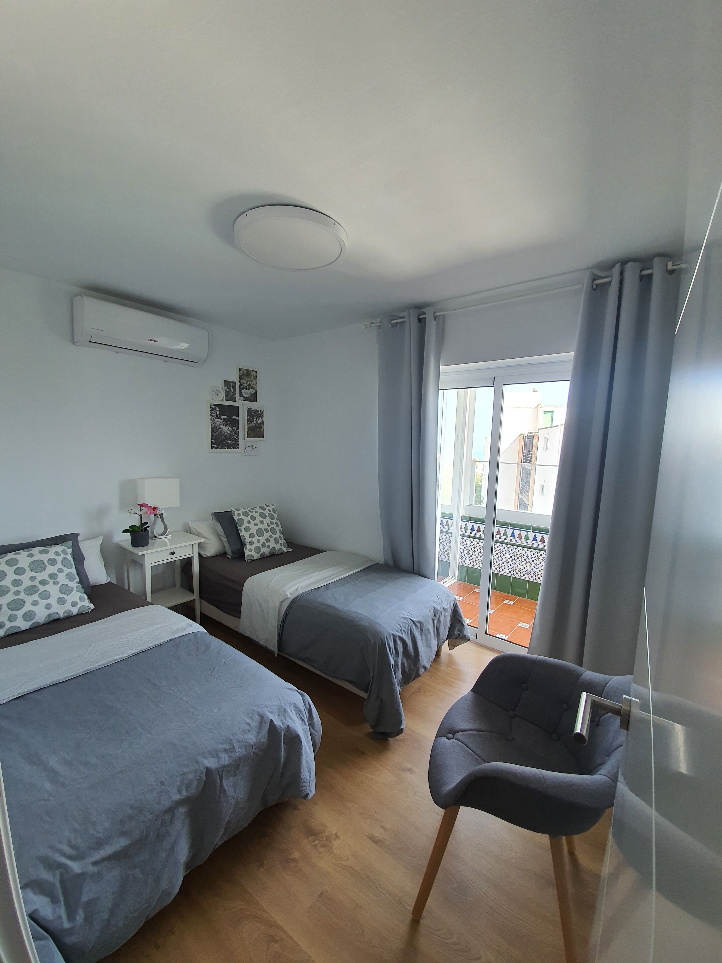 Une chambre d’hôtel avec deux lits, une petite table, une chaise, un appareil de climatisation et une vue sur l’extérieur.