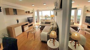 Una sala de estar moderna con sofá, mesa de centro y televisor.