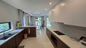 A modern kitchen with a central island, built-in appliances, and a view to the outdoors. - Nova Villas Phu Quoc (Phu Quoc)