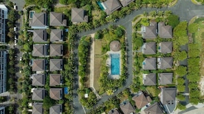 Vista aérea de un barrio residencial con varias casas, una piscina y abundante vegetación.