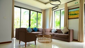 A spacious living room with a sofa set, a coffee table, and large windows with curtains. - Nova Villas Phu Quoc (Phu Quoc)