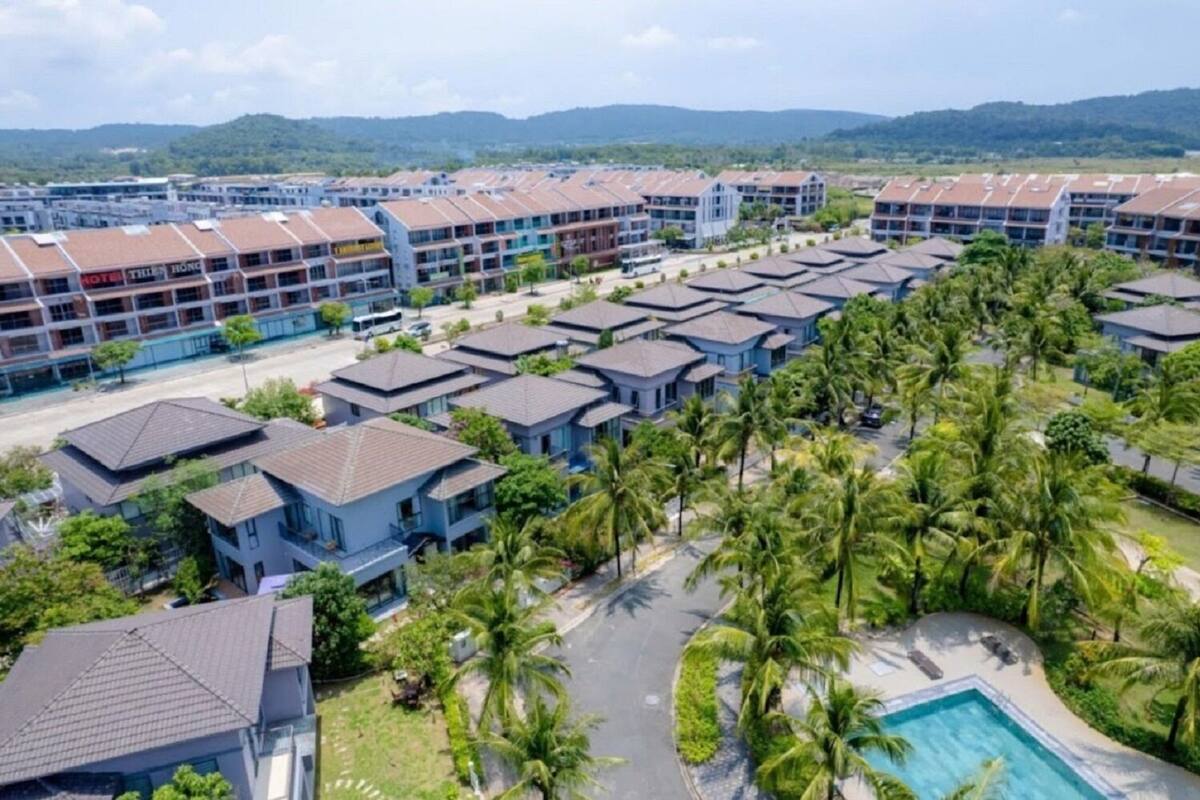 A hotel with multiple-story buildings, a pool area, and palm trees.