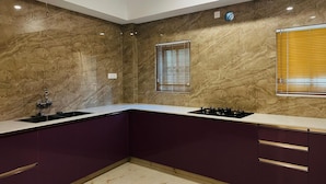 Una cocina moderna con paredes de mármol, estufa a gas y armarios morados.