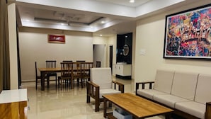 Una sala de estar moderna con comedor, un sofá, una mesa de centro y un cuadro abstracto grande.