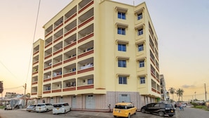 Un immeuble à plusieurs étages doté d’une façade plate, de nombreux balcons et d’une entrée au niveau du sol.