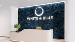 A reception desk with a dark marble wall behind it, and the words 'WHITE & BLUE' prominently displayed. - WHITE & BLUE (New Delhi)