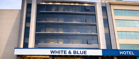 Ein Hotel mit moderner Fassade, großen Fenstern und einem Schild mit der Aufschrift 'WHITE & BLUE HOTEL'.