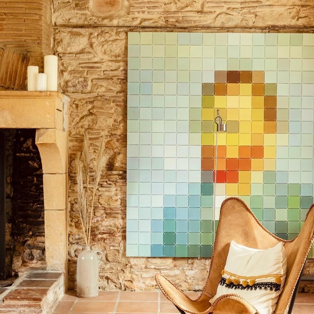 Eine Steinsäule mit Wandkunst aus Mosaikfliesen und einem Ledersessel.