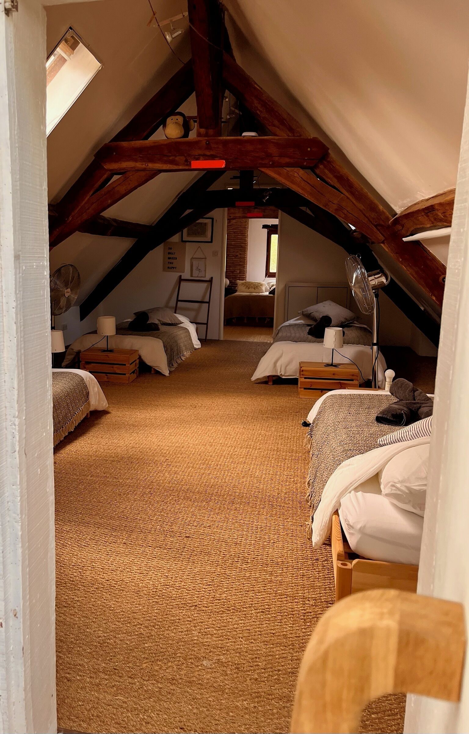A cozy attic bedroom with two beds, a wooden ceiling, and a rustic aesthetic.