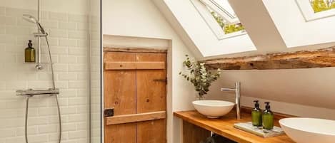 Un baño moderno con tragaluz, puerta de madera y un lavabo de diseño.