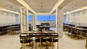 Un restaurant spacieux, doté de colonnes en marbre, de nombreuses tables et d’un lustre moderne.
