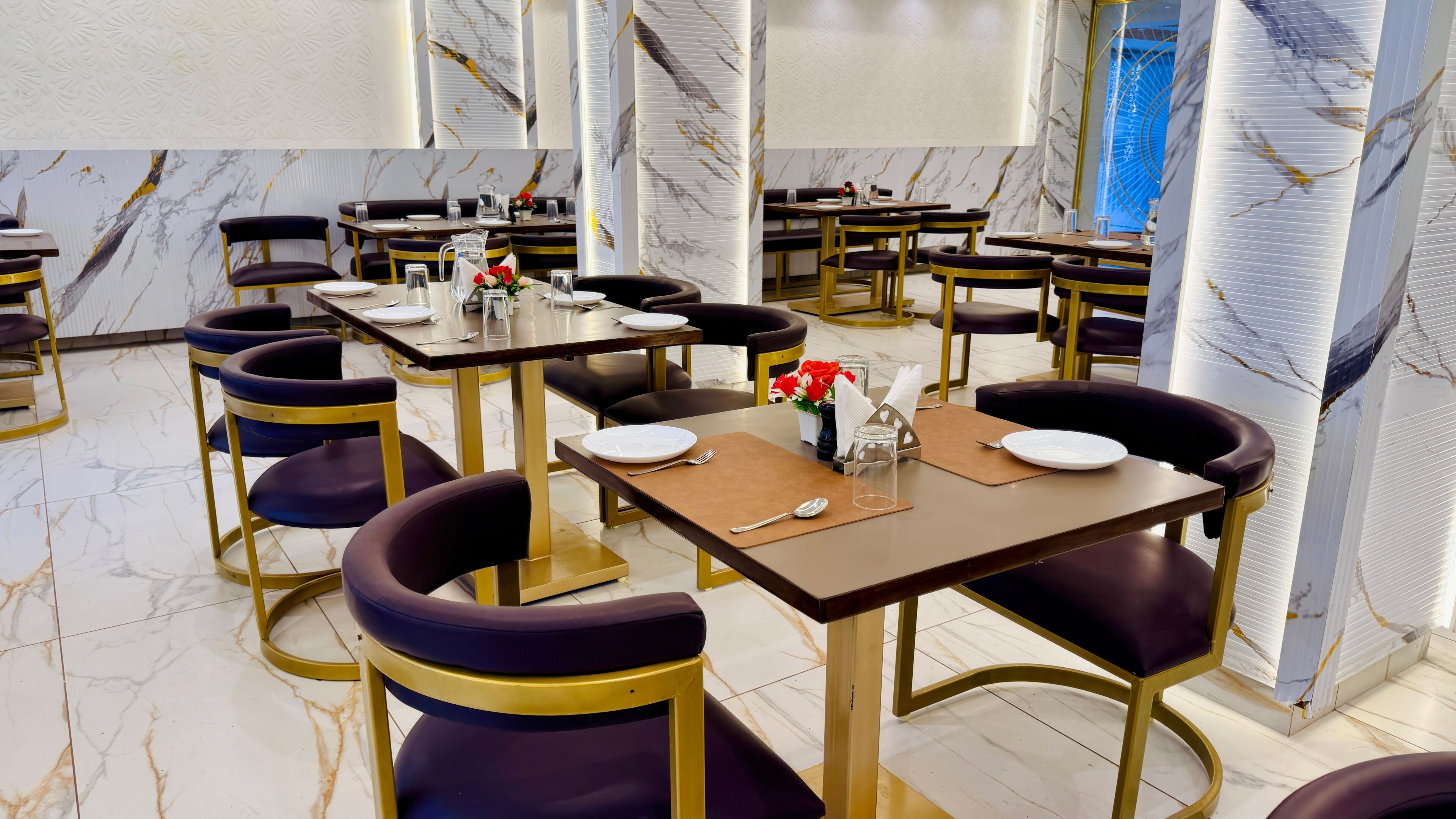 A restaurant with marble walls, gold-framed tables, and purple chairs.
