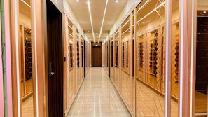 A corridor with mirrored walls and a polished floor, leading to a door at the end.