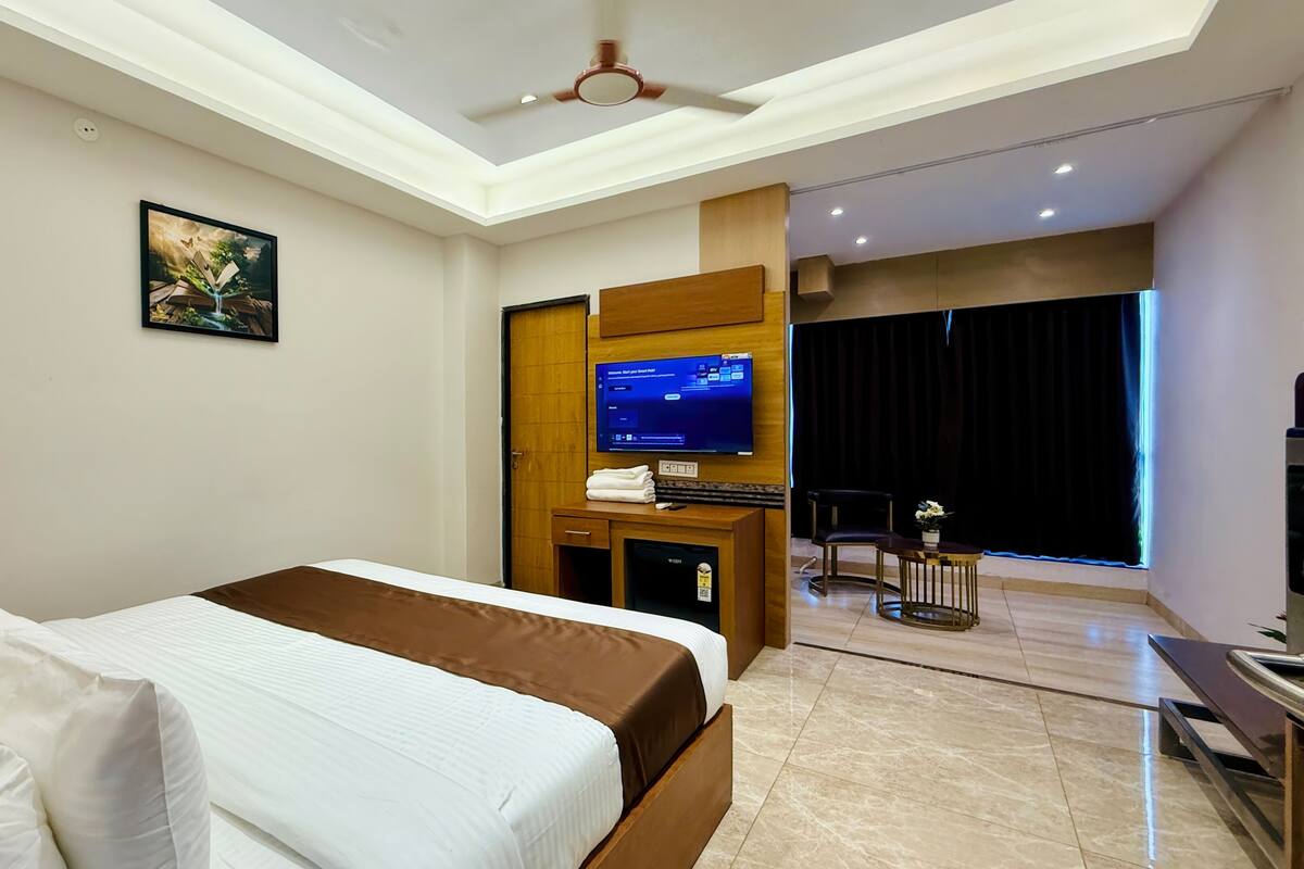 Una camera d'albergo con un letto, una scrivania con un computer, una televisione e vista all'esterno.