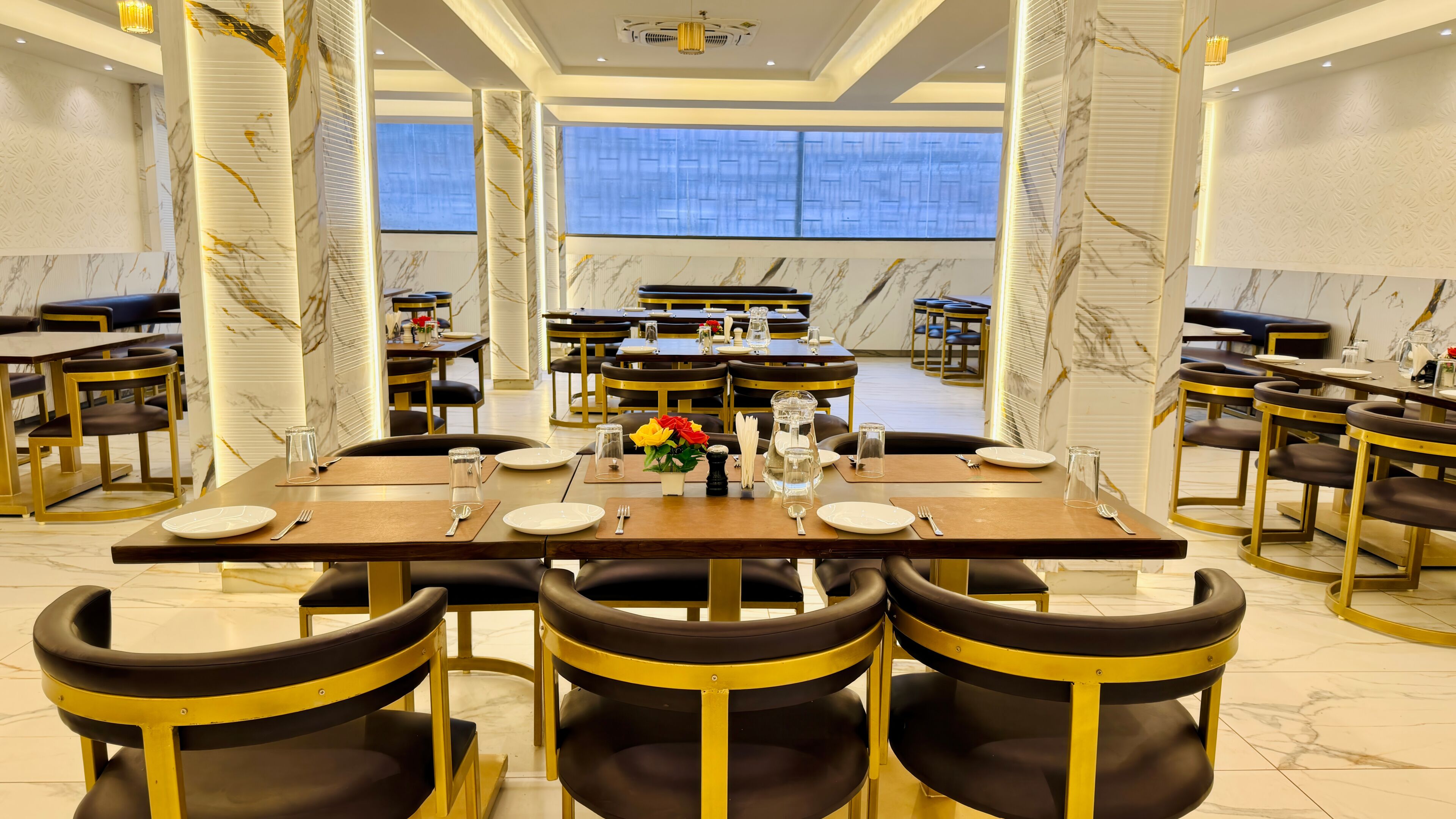 Un restaurante con paredes de mármol, sillas con marcos dorados y mesas dispuestas para comer.