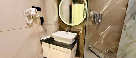 A modern bathroom with a glass shower enclosure, a white sink, and a round mirror.