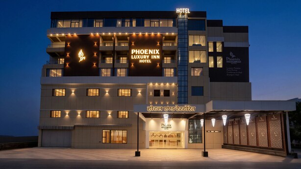Un hôtel à plusieurs étages, reconnaissable à son enseigne bien visible indiquant « Phoenix Luxury Inn Hotel ».