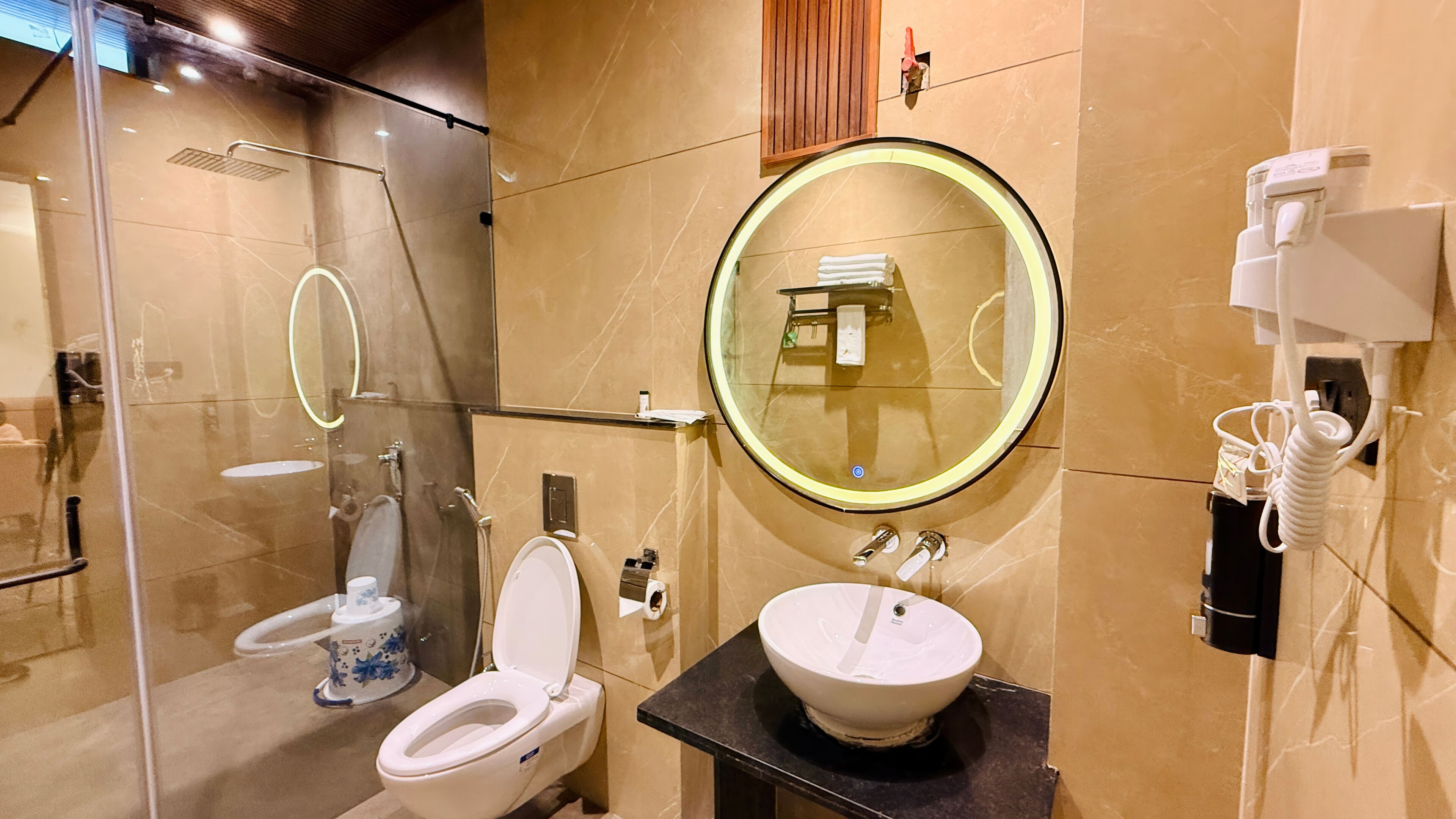 Ein modernes Badezimmer mit einer Duschkabine, einer Toilette, einem Waschbecken mit Spiegel und einem Handtuchhalter.