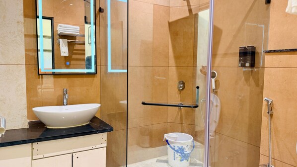 A modern bathroom with a glass-enclosed shower, a white sink, and a hand dryer. - Pheonix Luxury Inn Hotel (Pithampur)