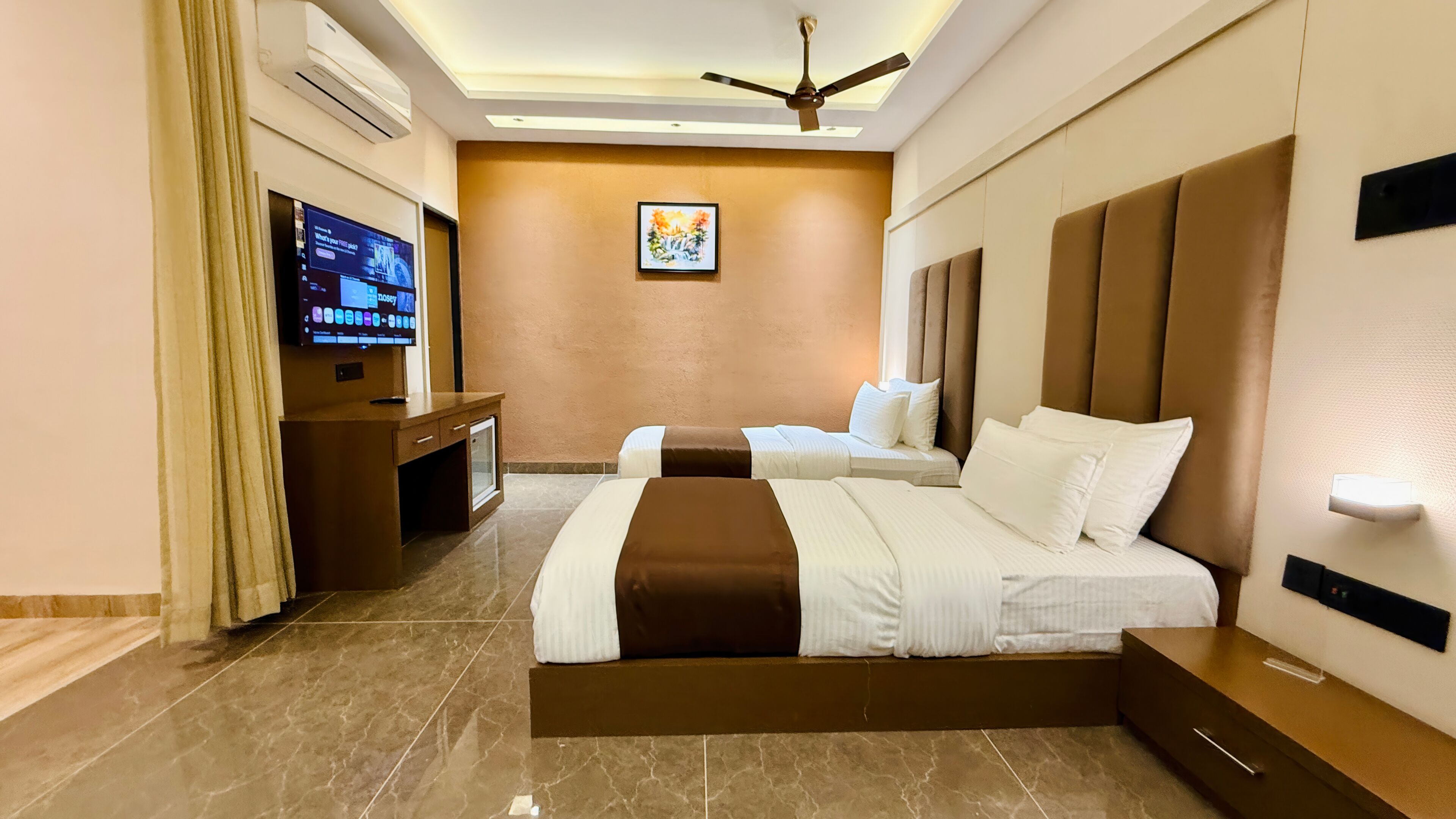 A hotel room with a bed, a desk, a television, and a ceiling fan.
