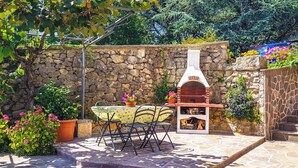 A stone wall, outdoor seating, and a pizza oven. - Cozy 2-bedroom apartment Near the Sea in Ika - with Terrace, AC & Free Parking (Ika)