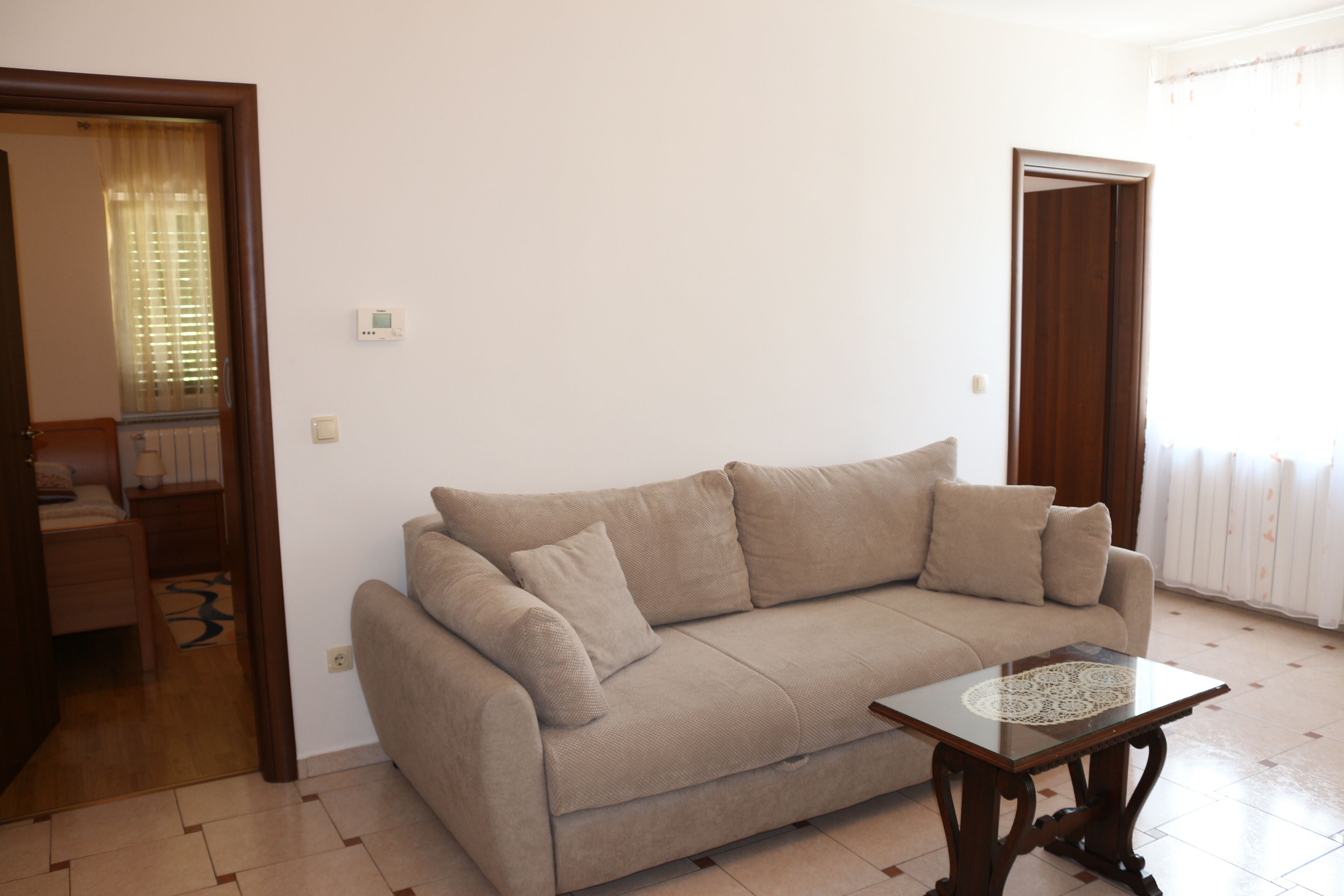 A living room with a beige sofa, a glass coffee table, and a wooden floor.