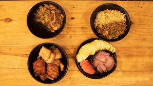 Four bowls of food on a wooden table.