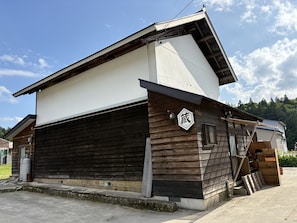 A two-story building with a garage door, wooden siding, and a sign with Japanese characters.