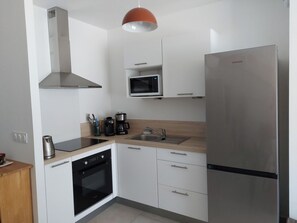 Eine moderne Küche mit Edelstahl-Kühlschrank, integriertem Mikrowellenherd, Backofen und Dunstabzugshaube.