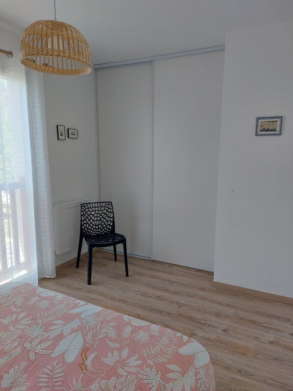 A room with a bed, a chair, a wardrobe, and a hanging light fixture. - DUPLEX house in a rural village near the ocean (Lit-et-Mixe)