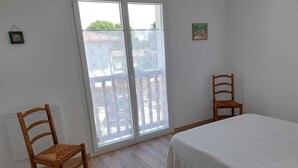 A room with a bed, two wooden chairs, a window with a view, and a small picture on the wall. - DUPLEX house in a Landes village near the ocean (Lit-et-Mixe)
