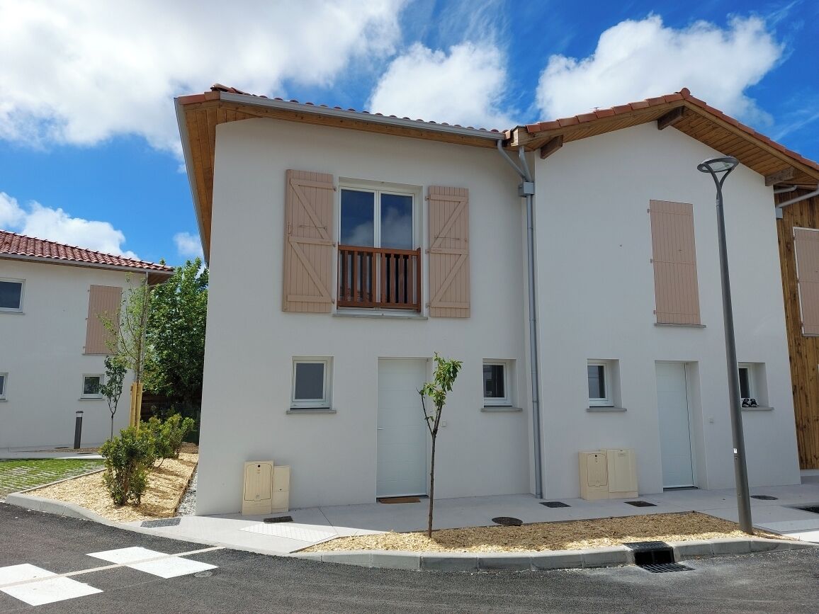 A modern building with a flat roof, white exterior walls, and wooden shutters on the windows. There are small windows and a door visible, and a street lamp is present.