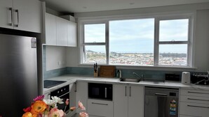 Una cocina moderna con un ventanal grande, electrodomésticos de acero inoxidable y vistas a un pueblo.