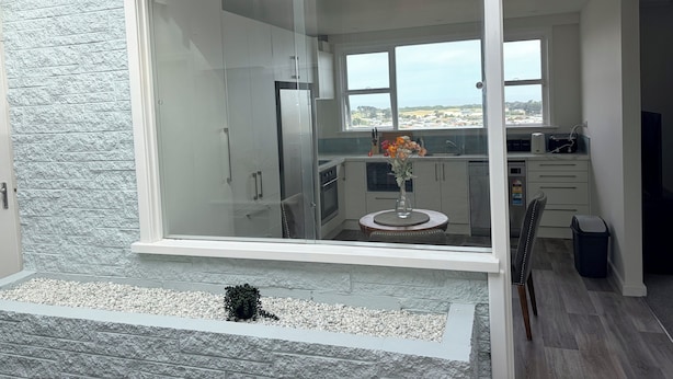 Una cocina moderna con un amplio ventanal corredero, pared con textura de piedra y vistas al paisaje.