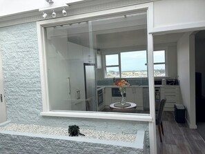 A modern kitchen with a large glass sliding door, a stone-textured wall, and a view of the landscape.