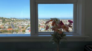 Una ventana con vista a un pueblo y un florero con flores en el alféizar.