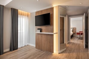 A modern hotel room with a wooden accent wall, a mounted TV, and a red chair. - Holiday Inn Express And Suites Portimao by IHG (Portimao)